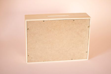 Vista trasera de alcancía de madera con fondo de MDF oscuro y tornillos de sujeción